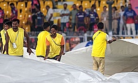 Ground staff brings more covers on the ground as rain delays the IPL