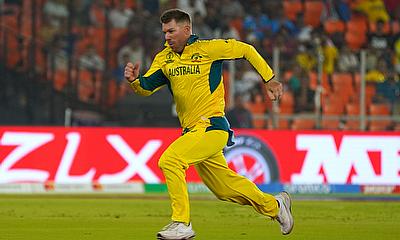 Australia's David Warner runs behind the ball to save a run alt=
