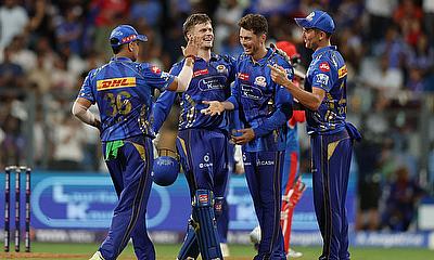 Mumbai Indians' Mitchell Santner celebrates with teammates after taking the caught and bowled wicket of Delhi Capitals' Vipraj Nigam